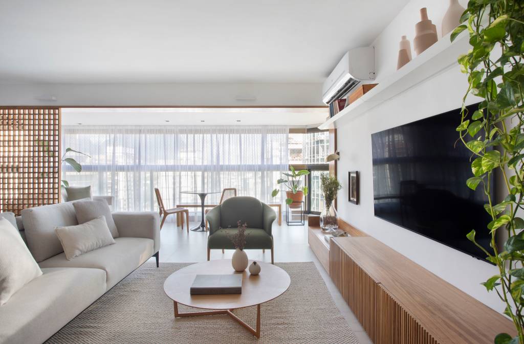 8-reforma-deixa-ape-de-150-m-2-mais-iluminado-e-com-ambientes-leves Sala de estar com armário de madeira, mesa de centro de madeira, poltrona cinza e sofá claro