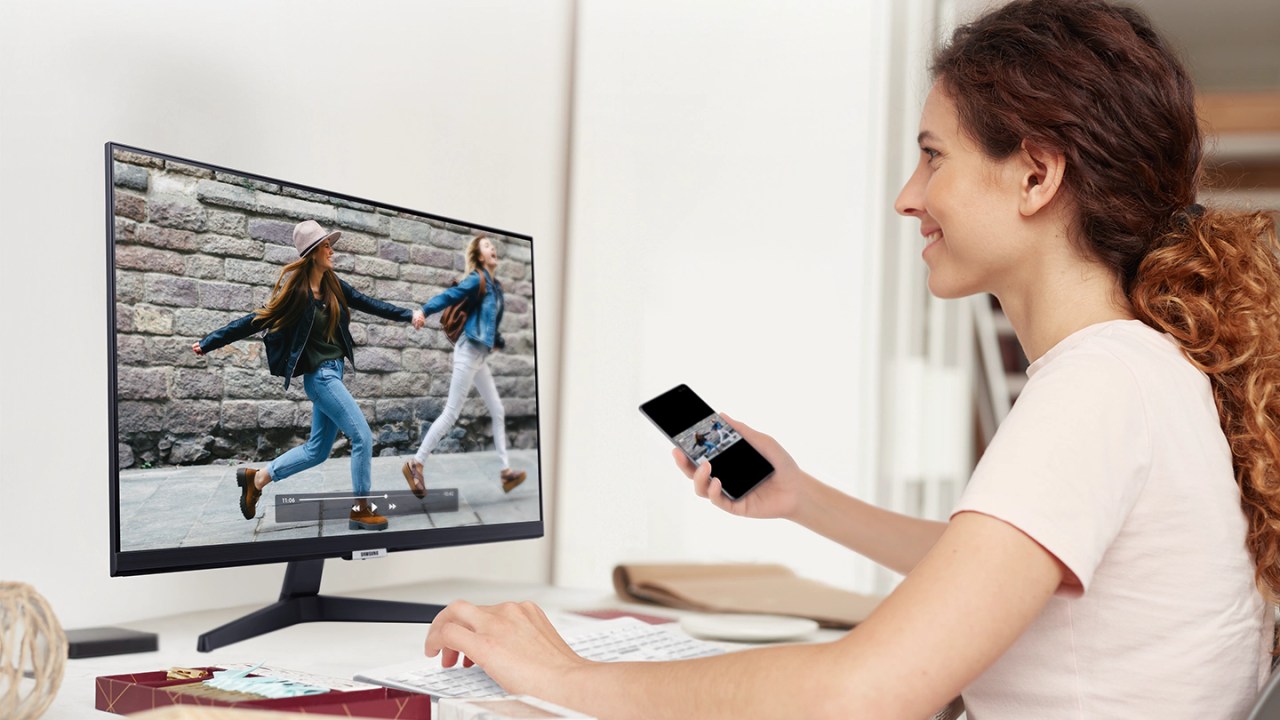 Mulher assiste a vídeo do celular com imagem espelhada no monitor Samsung M5.