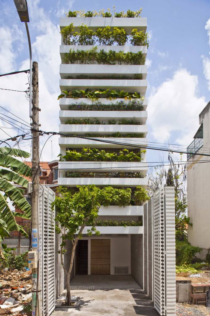 biofilia-fachada-verde-traz-benefícios-a-casa-vietna-hiroyuki-ori-jardim-vertical-fachada-terreno-estreito Foto mostra fachada de casa em terreno estreito, com alguns pavimentos em que se vê caixas de concreto com plantas formando um enorme jardim vertical.