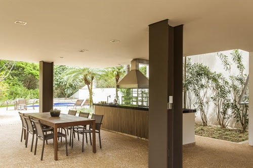churrasqueira-como-escolher-melhor-modelo-eduardo-pozella-churrasqueira-varanda-gourmet-piscina Foto mostra área gourmet externa com churrasqueira, mesa de refeições e piscina.