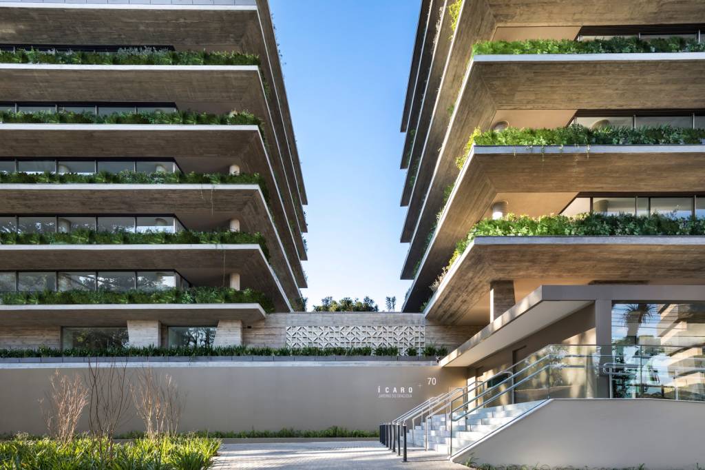 Foto mostra fachada de edifício residencial com abundância de plantas e floreiras nas varandas dos apartamentos.