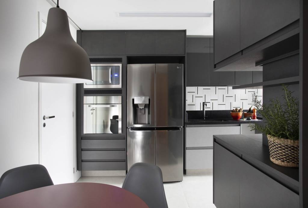 Apartamento- Barra da Tijuca- BETA ARQUITETURA Cozinha com armários em preto opaco, detalhes geométricos na parede e duas gavetas em cinza-claro