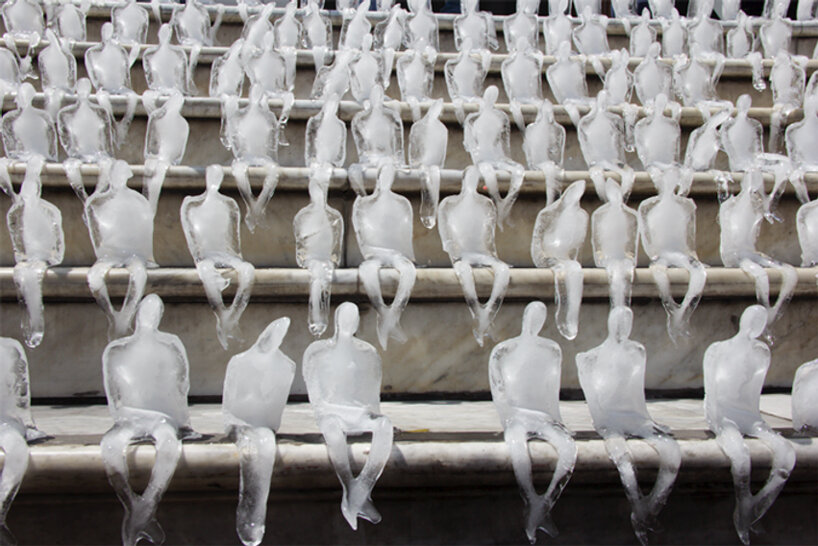 Essas esculturas de gelo alertam sobre mudanças climáticas-Designboom Néle Azevedo (14) Pequenas esculturas de gelo derretendo de pessoas sentadas uma ao lado da outra de cabeças levemente baixas numa escadaria.