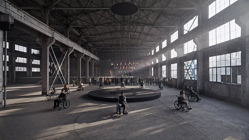 Esta instalação foi criada por pessoas com deficiência com a mente Designboom (2) Cadeirantes dispostos em volta de uma grande plataforma circular. Cena acontece dentro de um galpão.