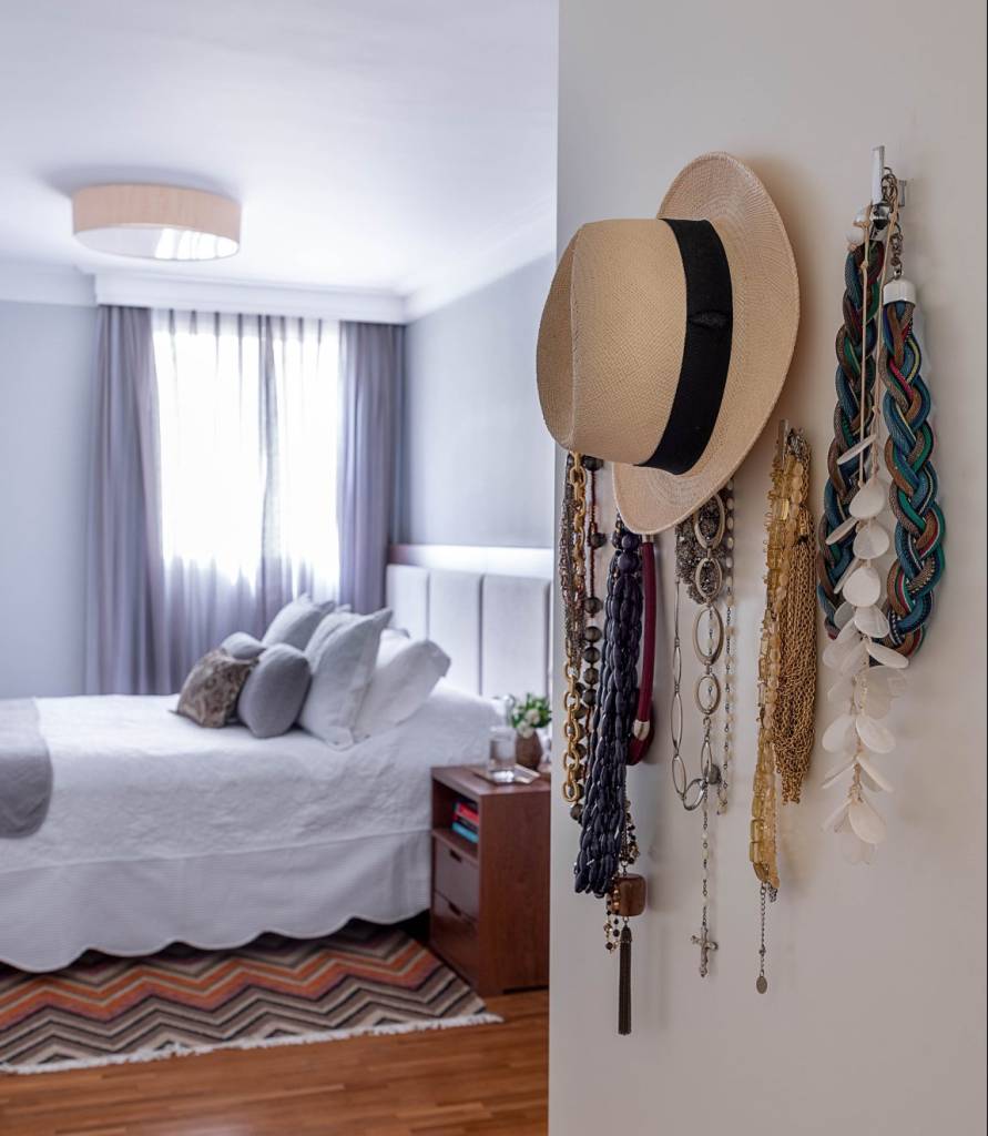 moveis-usados-nova-decoracao6 Quarto com chão laminado, cama com acolchoado branco, chapéu e objetos pendurados na entrada do cômodo