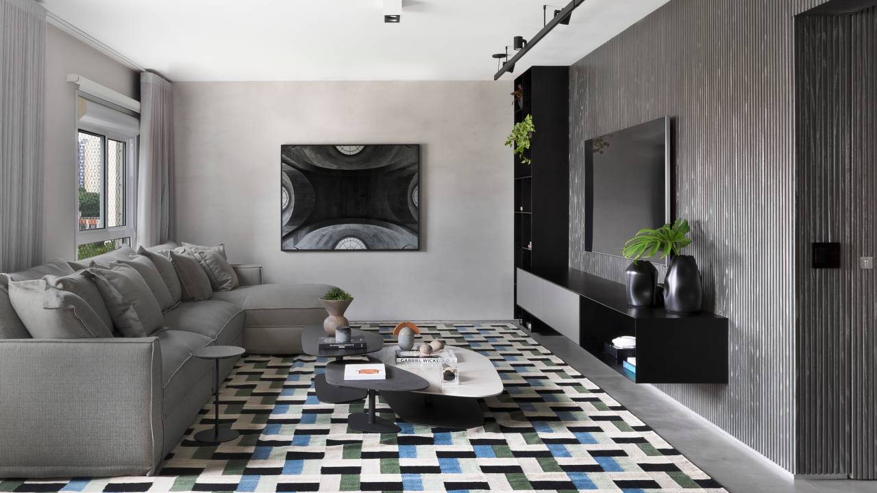 Sala de estar em tons de cinza com tapete azul e verde