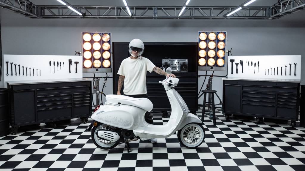 10 peças de design criadas por celebridades Dezeen (7) Justin Bieber posa atrás de scooter branca.