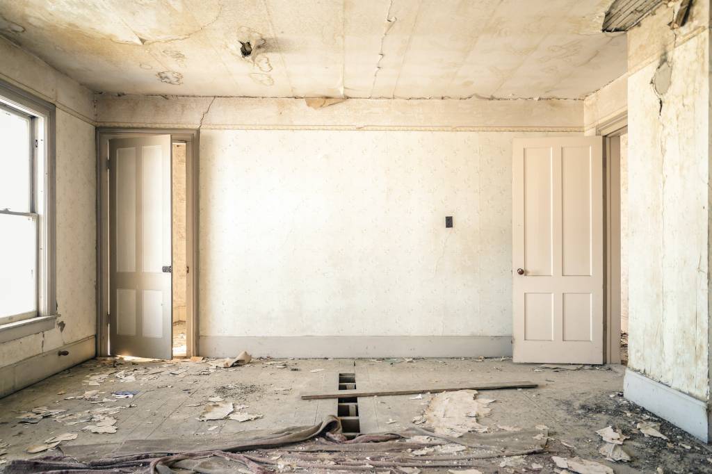 5-erros-comuns-em-reformas-nolan-issac-unsplash-demolição-reforma-casa Foto mostra sala de casa com piso destruído, paredes e teto com danos.