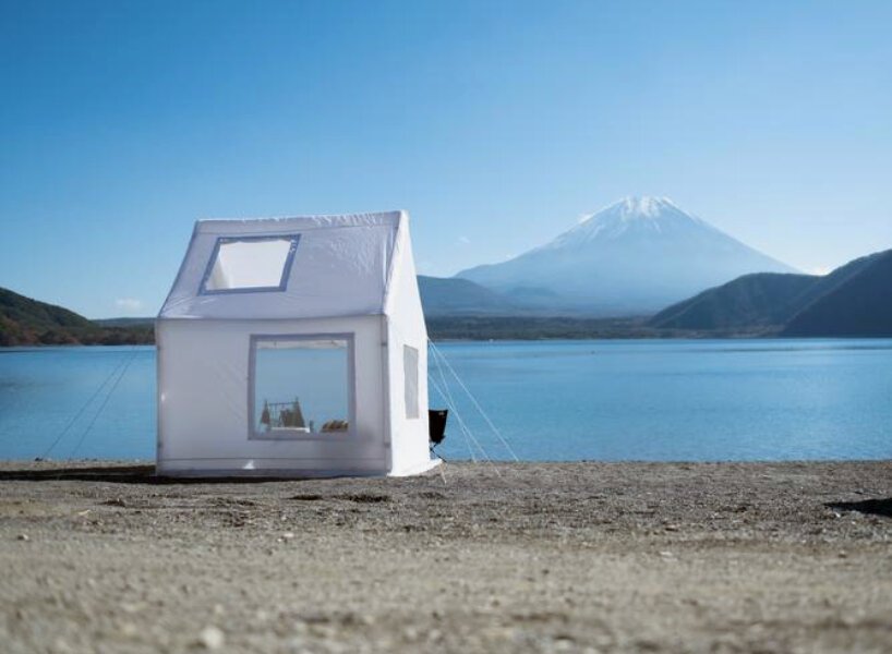 Conheça esta casinha de acampamento inflável Tsutaya Electrics (1) Casa inflável branca a beira de um grande lago.