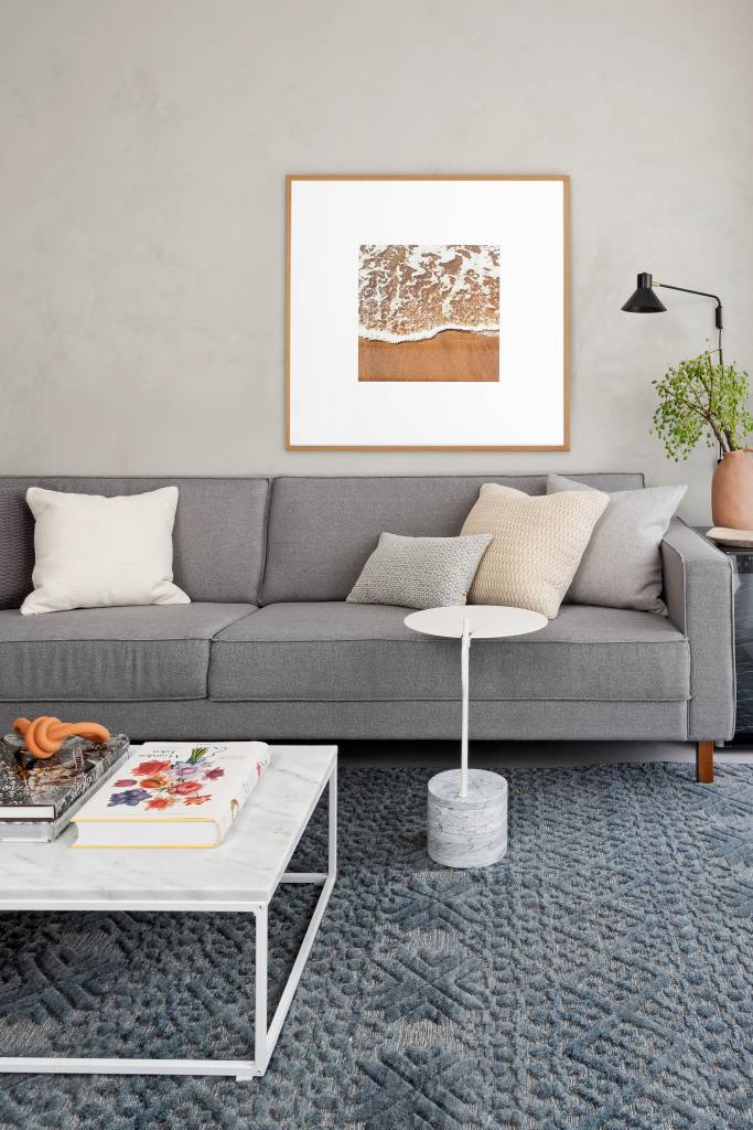 Cozinha-com-marcenaria-rosa-é-destaque-neste-apê-Projeto-Ana-Toscano-Arquitetura-Foto-Julia-Ribeiro-sofa-cinza-tapete-azul Sala de estar com sofá e obras de arte