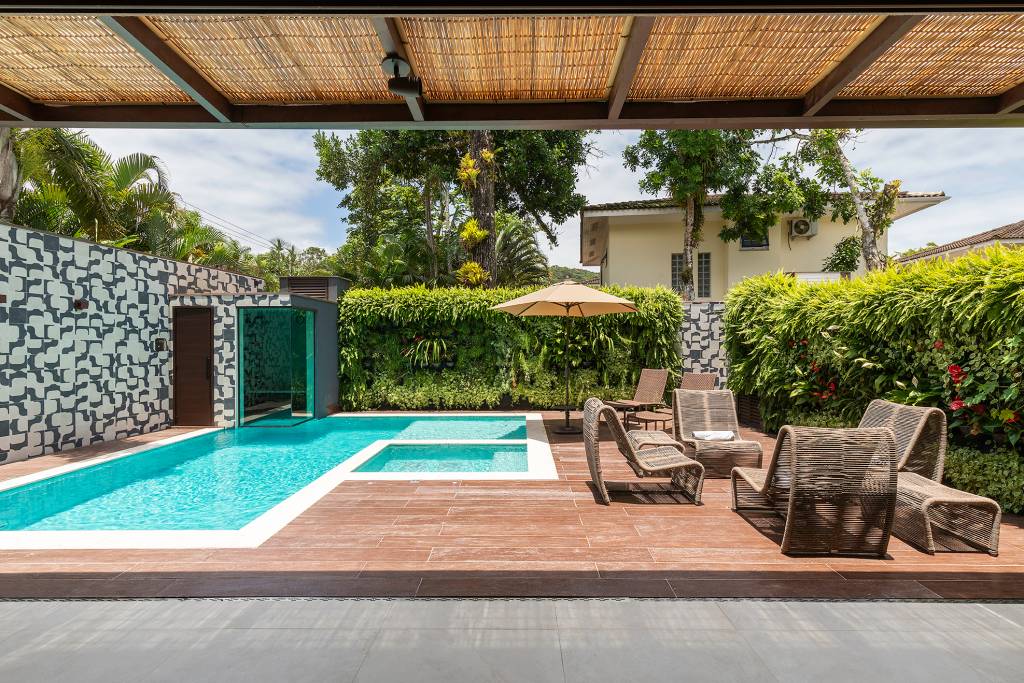 Decorações-em-materiais-naturais-marcam-esta-casa-de-500-m2-Projeto-Concretize-Interiores-Foto-Raphael-Briest-piscina-cadeiras-area-externa Área da piscina com parede verde