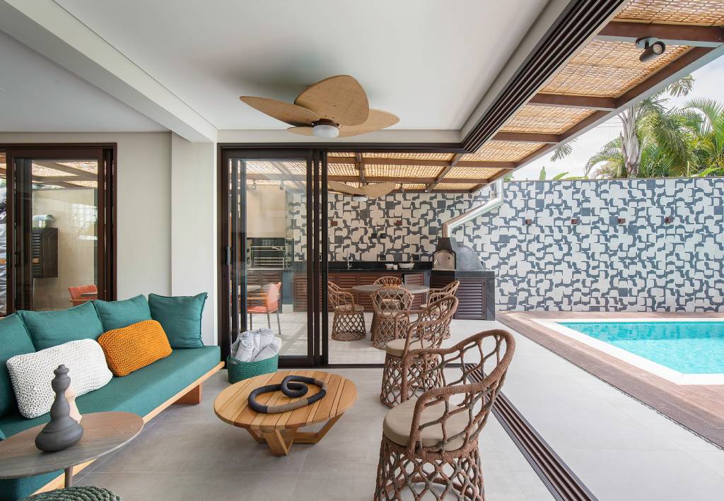 Decorações-em-materiais-naturais-marcam-esta-casa-de-500-m2-Projeto-Concretize-Interiores-Foto-Raphael-Briest-varanda-sofa-verde Sala de estar integrada com a varanda