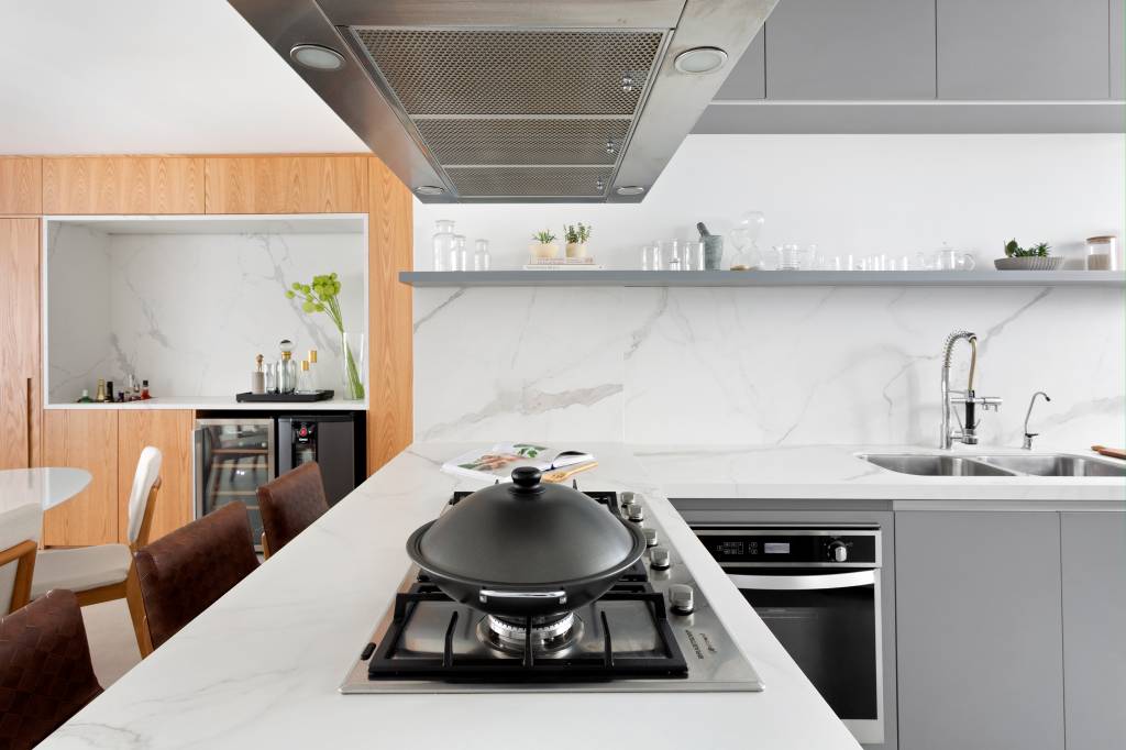 Painel-de-madeira-que-percorre-por-toda-a-sala-e-destaque-neste-ape-de-112m2-Projeto-Doob-Arquitetura-Foto-Julia-Ribeiro-cozinha-ilha-banquetas Bancada com cooktop na cozinha