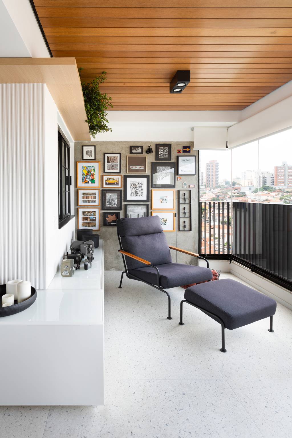 Pontos-sutis-de-cor-se-destacam-neste-ape-de-142 m2-Degradê-Arquitetura-e-Interiore-foto-Julia-Ribeiro-varanda-fotos-cameras-poltrona Poltrona posiciona em cantinho com máquinas e fotografias