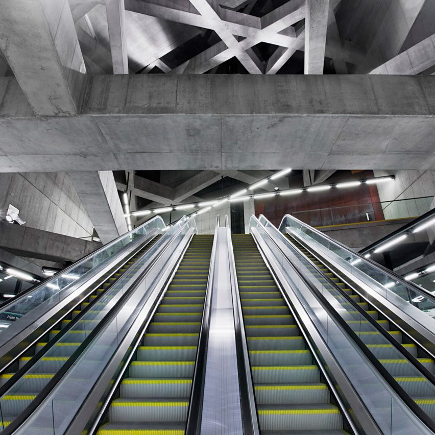 dez-estações-metro-século-21-hungria-divulgação Escadas rolantes vistas de baixo para cima, com teto em vigas de concreto formando uma espécie de trama.