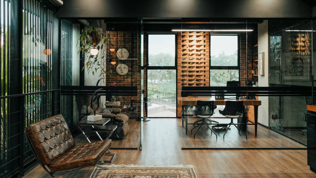 edificio-corporativo-medellin-arquitetura-acolhedora-mateo-soto-escritorio-piso-madeira-tijolinho Escritório tem decoração que lembra uma casa: paredes de tijolinho, piso de madeira, plantas e tapetes.