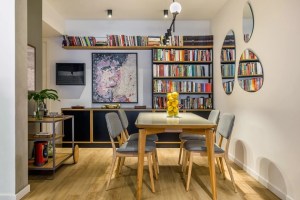 Sala de jantar com piso vinílico que imita madeira, bufê ao fundo com estante de livros e um carrinho de chá na lateral.