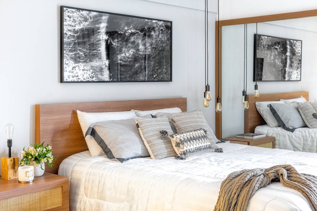 ape-duplex-de-70m-traz-praia-para-cidade-Zabka Closs Arquitetura-fotos-Renata Freitas-quarto-cama-espelho-fotografia Quarto com cama de casal; fotografia na parede; luminária; mesinha lateral