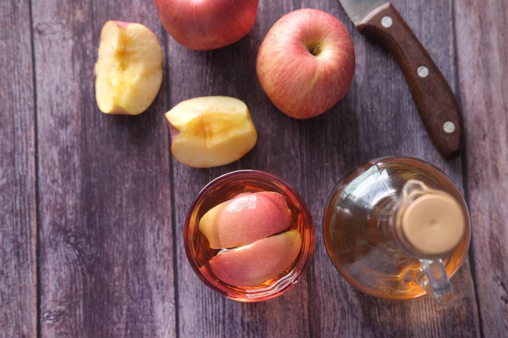 fazer-vinagre-com-restos-de-maca-Towfiqu barbhuiya-unsplash-02 Frasco de vidro com vinagre com maçã cortada em mesa de madeira