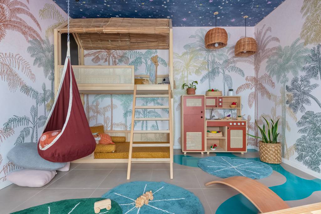 Floresta Encantada, por Stephanie Ribeiro e Baby Abdalla. Com 19,38 m&sup2;, o quarto com brinquedoteca foi inspirado no desenho Peter Pan, da Disney. A ideia das arquitetas foi criar um ambiente l&uacute;dico de aventura e fantasia onde a crian&ccedil;a pode se divertir e brincar. A cria&ccedil;&atilde;o de elementos simples que podem instigar a imagina&ccedil;&atilde;o, como o adesivo no piso e o teto estrelado, ganham destaque junto a Beliche Casa na &Aacute;rvore, lan&ccedil;amento da Muskinha e papel de parede desenvolvido em parceria com a Manual Design especialmente para o ambiente.