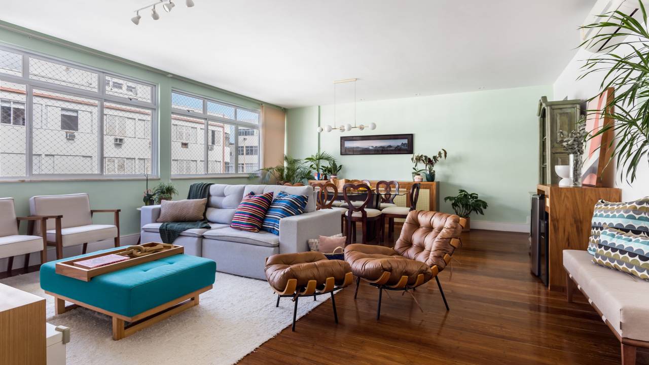 Sala de estar com poltrona, mesa de centro, plantas, parede verde