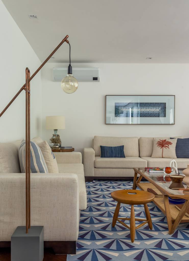 Sala de estar com sofás brancos e luminária de piso