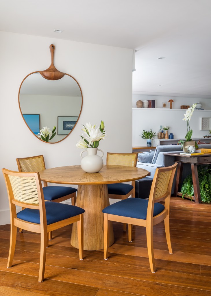 Sala de jantar com mesa redonda em madeira e espelho