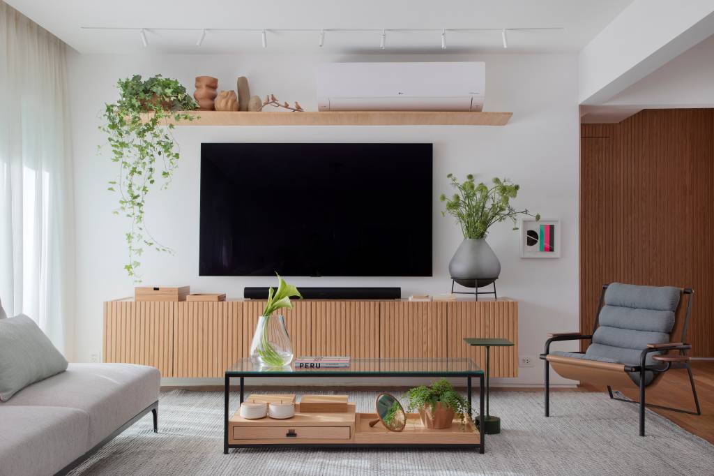 ape-160m-cama-retratil-escondida-painel-madeira-ripada-maia-romeiro-arquitetura-fotos-denilson-machado-02-sala-tv-rack Sala; sala de tv; rack de madeira; tapete; poltrona; mesa de centro