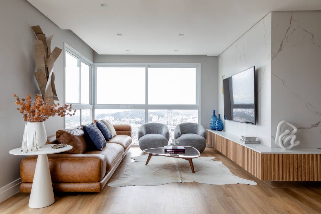 Piso vinílico; Sala de estar; sofá de couro; poltrona cinza; tapete vaca; sala de tv