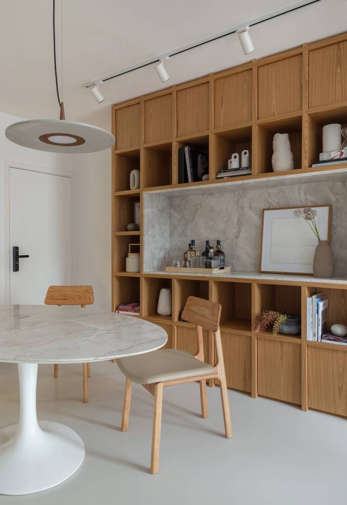 ape-90m-closet-quartos-renovados-estante-modular-joao-panaggio-fotos-luiza-schreier-10-sala-jantar Sala de jantar com paredes brancas, mesa redonda com tampo branco, cadeiras de madeira e estante de madeira