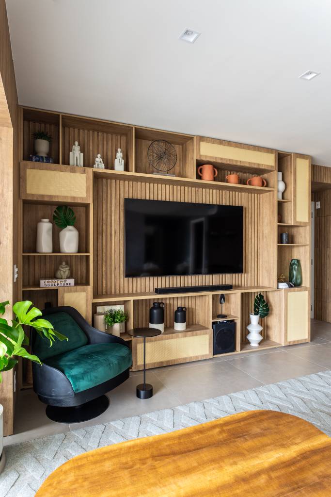 Sala de estar; sala de tv com painel de madeira ripada com nichos; poltrona verde