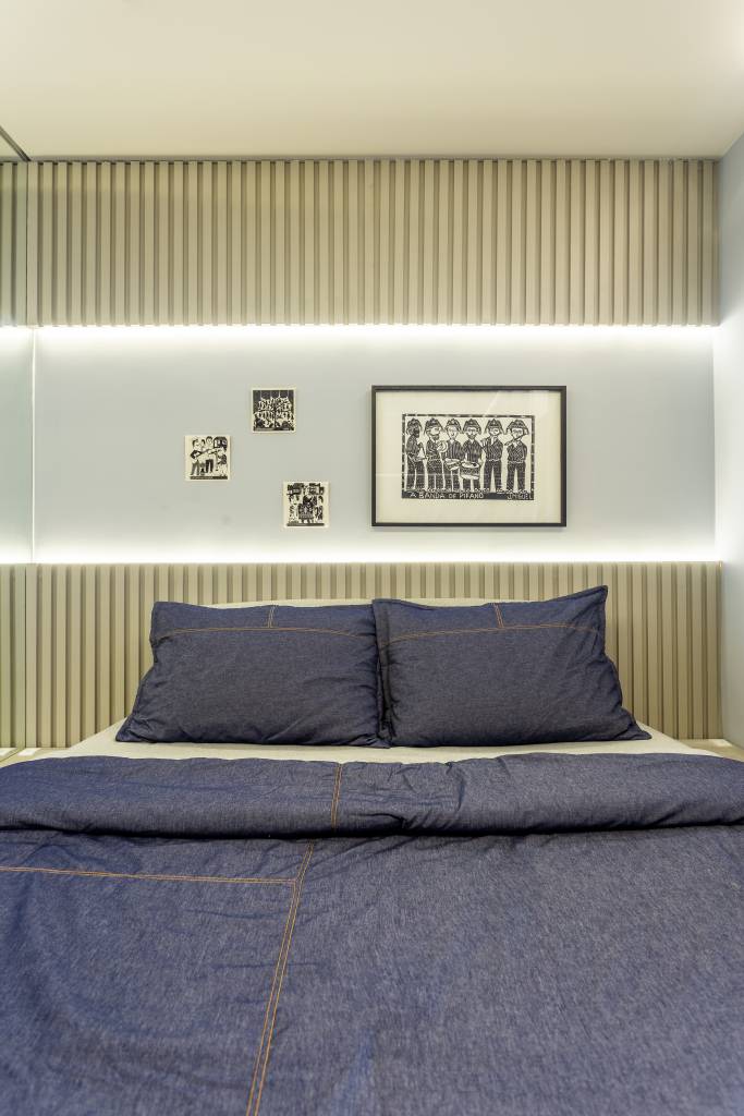 ape-95m-decoracao-influencia-nordestina-biofilia-llarquitetura-17-quarto Quarto com parede de madeira ripada e nicho iluminado acima da cama.
