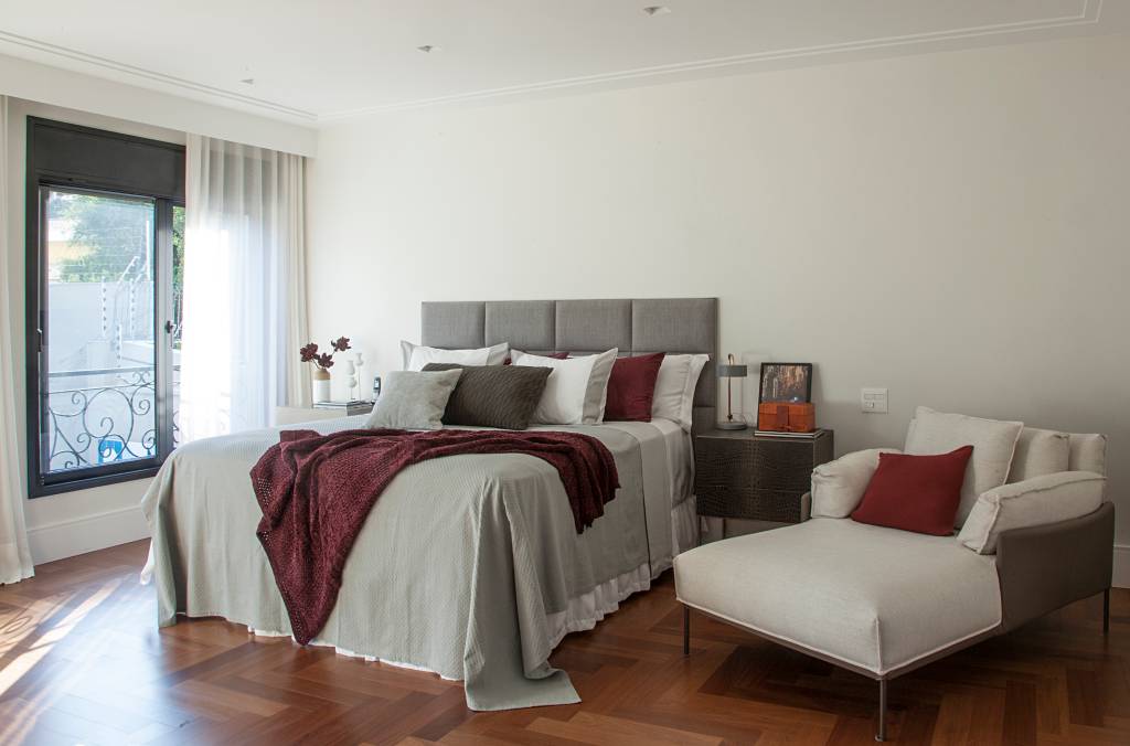 casa-tem-quarto-e-home-office-voltados-para-jardim-isabella-nalon-28 Quarto de casal com cabeceira acolchoada cinza e poltrona branca ao lado da cama.