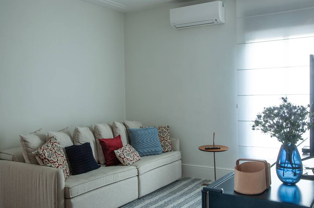 casa-tem-quarto-e-home-office-voltados-para-jardim-isabella-nalon-30 Sala íntima com sofá branco e tapete listrado; ar condicionado.