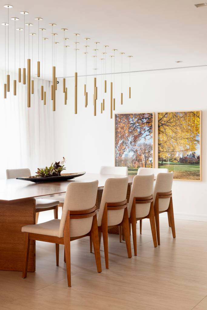 Sala de jantar com mesa de madeira e luminárias pendentes.