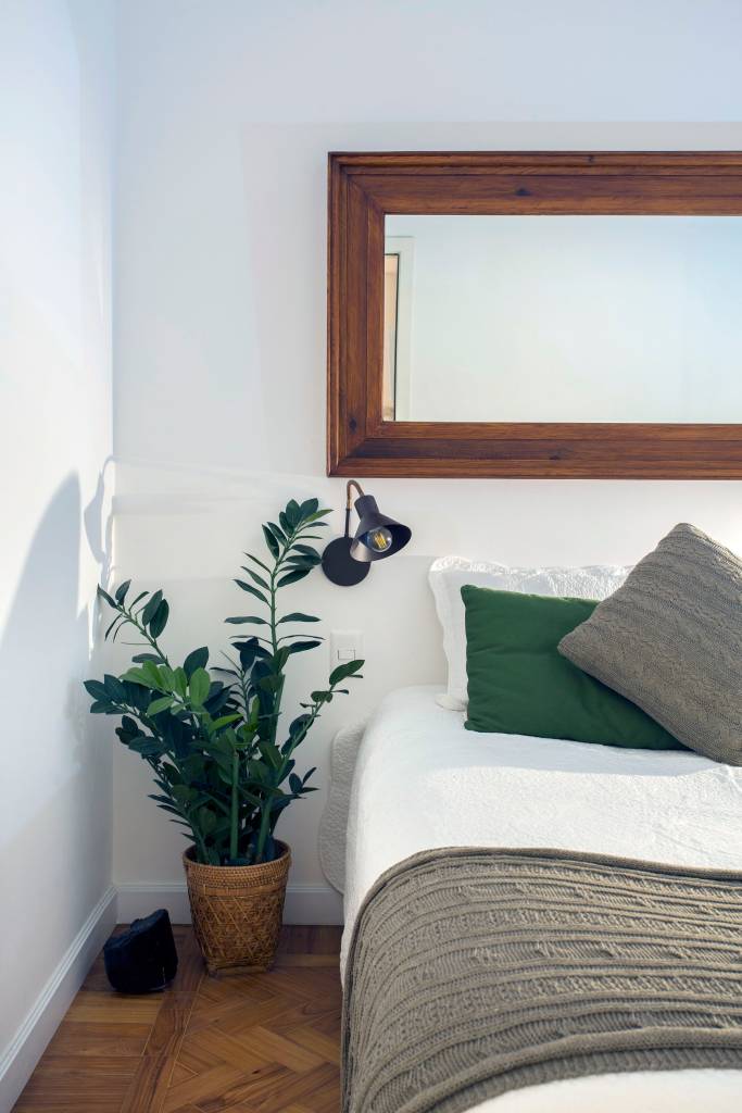 ape-de-70m-ganha-cara-nova-com-reforma-economica-ketlein-amorim-09-quarto Quarto com cama de casal, planta ao lado da cama e espelho.