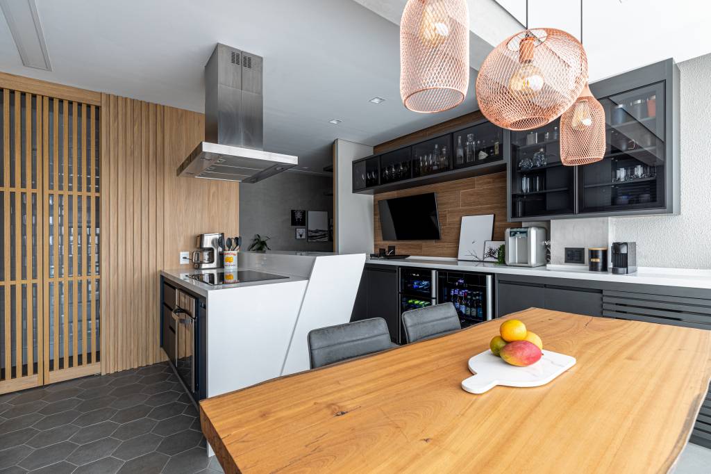 cozinha-protagonista-ape-66m-atmosfera-industrial-cadda-arquitetura-20 Varanda integrada com cozinha; mesa de madeira e bancada branca.