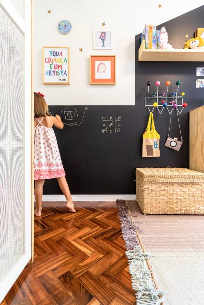 ganchos-cabideiros-na-decoracao-studio-km Quarto infantil com parede de quadro negro e cabideiro com ganchos coloridos.