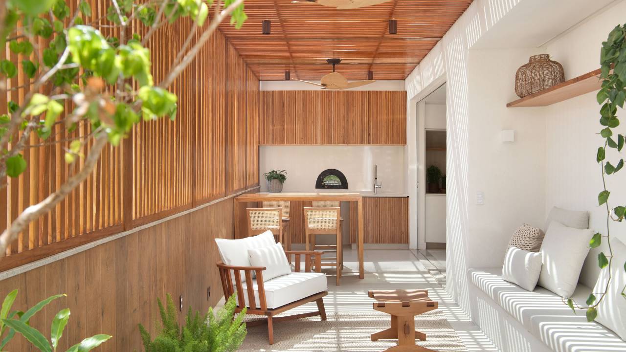 Área gourmet com cobertura de ripas de madeira e bancada de madeira.