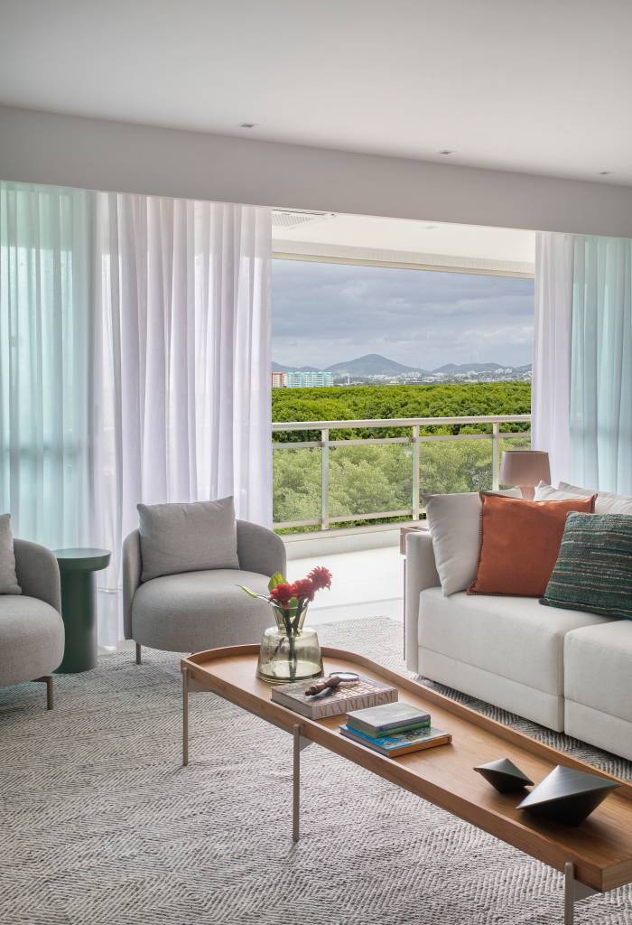 parede-verde-madeira-natural-ape-240m-amanda-miranda-02-sofa-poltrona Sala de estar com vista; sofá branco, poltronas e mesa de centro.