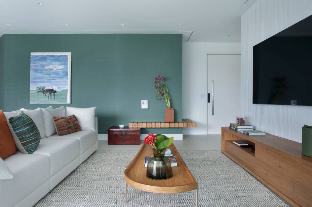 parede-verde-madeira-natural-ape-240m-amanda-miranda-03-sala Sala de tv com parede verde e mesa de centro de madeira.