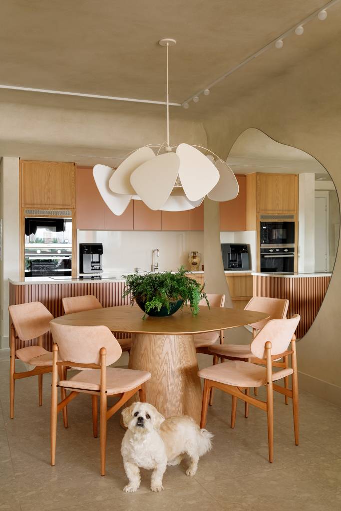 tons-areia-formas-arredondadas-atmosfera-mediterranea-ape-gustavo-marasca-10-jantar Sala de jantar integrada com cozinha; mesa redonda, cadeiras de madeira e luminária.