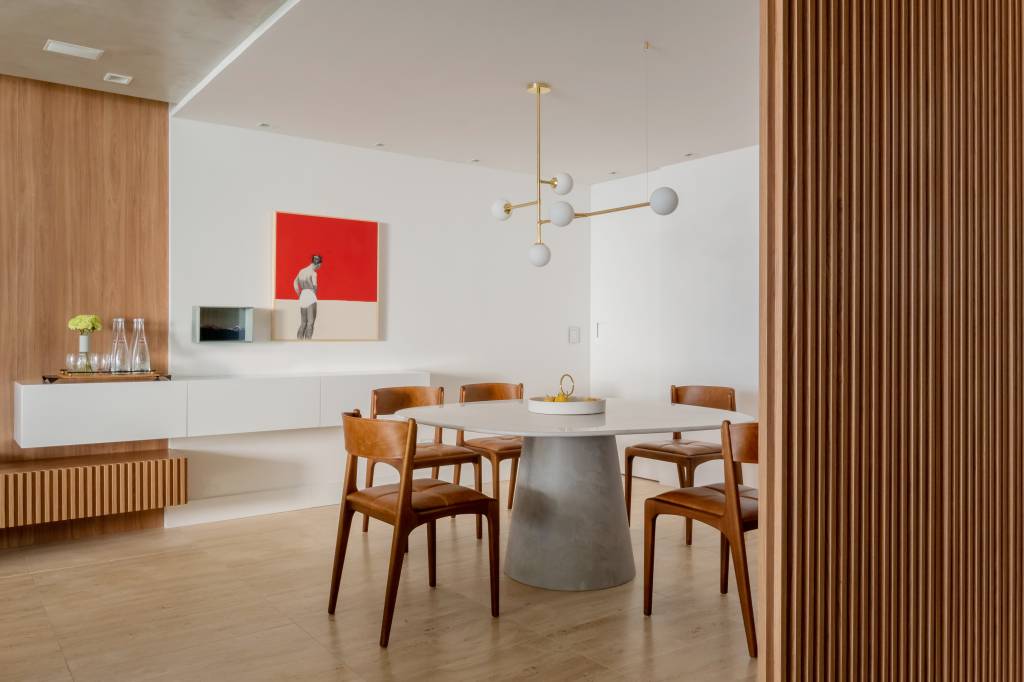 Sala de jantar com madeira; mesa redonda, cadeiras de madeira, buffet branco e quadro