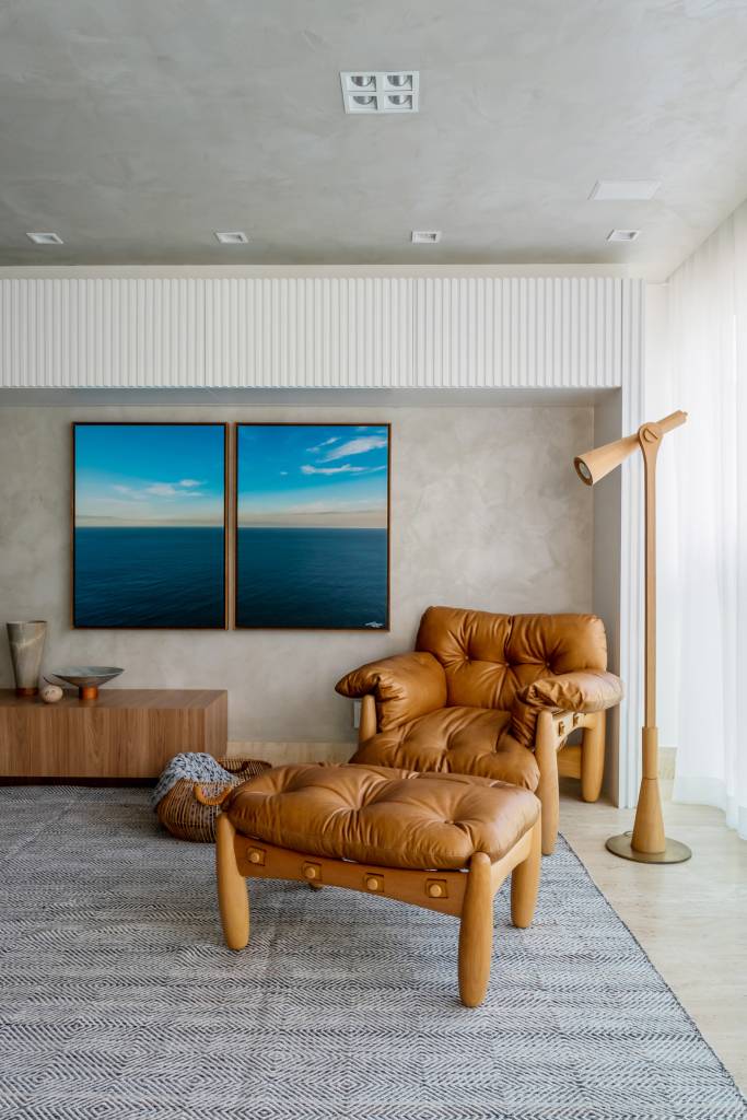 toques-de-azul-referencia-mar-ape-elegante-160m-studio-plano-arquitetura-11-poltrona Sala de estar revestida de cimento queimado com banco de madeira e estante de marcenaria branca. Poltrona Mole