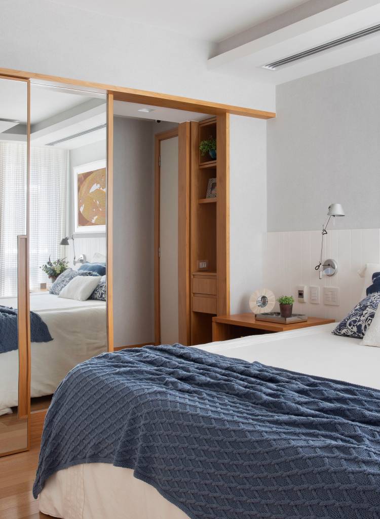 Quarto com closet, com cabeceira branca. cama de casal e roupa de cama azul