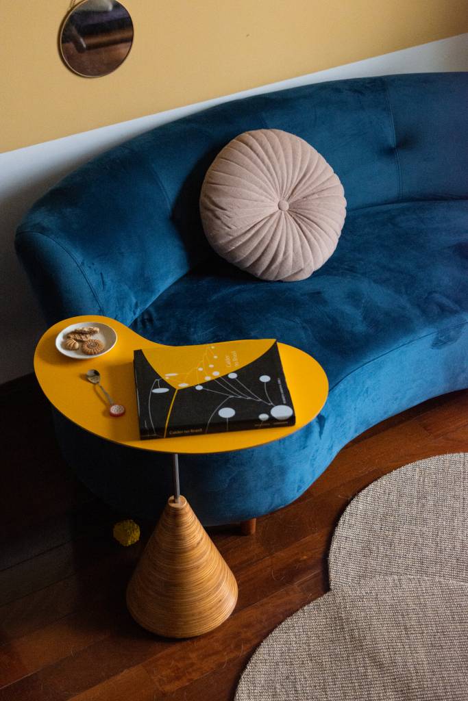 ape-80m-decoracao-memorias-paleta-de-cores-terrosa-sertao-arquitetos-13-sofa-azul Sofá curvo azul com mesinha lateral amarela.