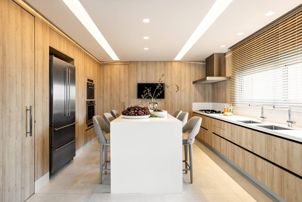 Cozinha ganha layout clean e elegante com revestimento amadeirado
