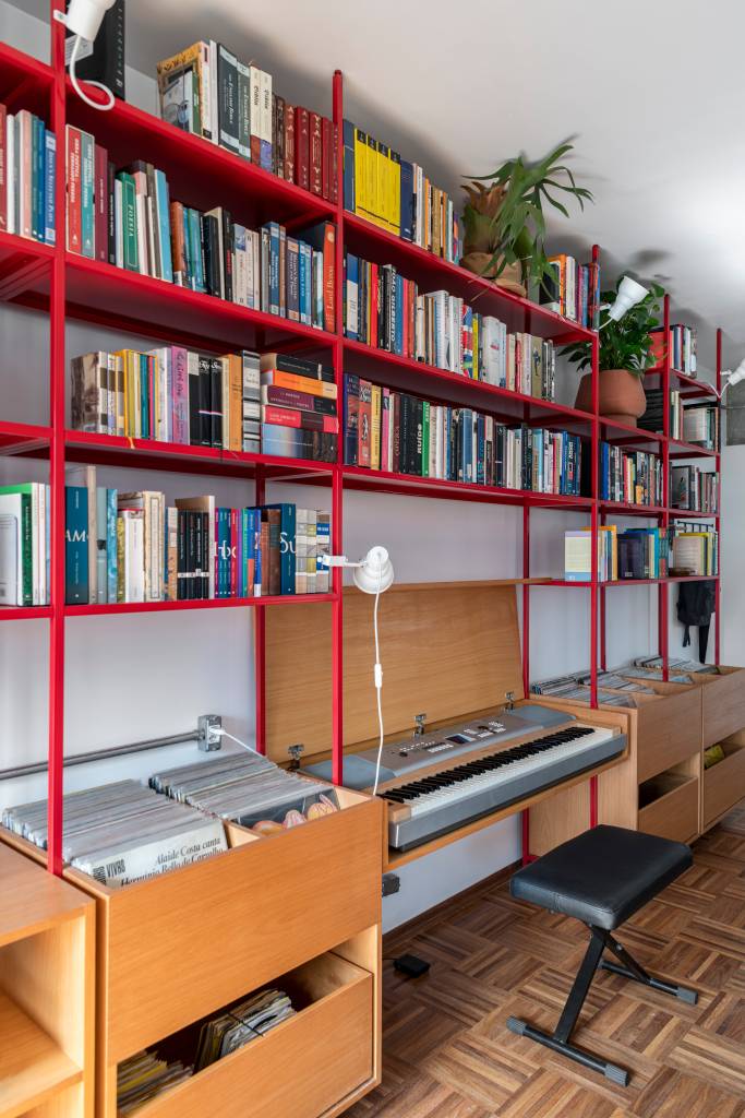 estante-serralheria-vermelha-destaque-ape-100m-cota-760-arquitetura-04 Estante de serralheria vermelha com livros, banco e espaço para discos de vinil.