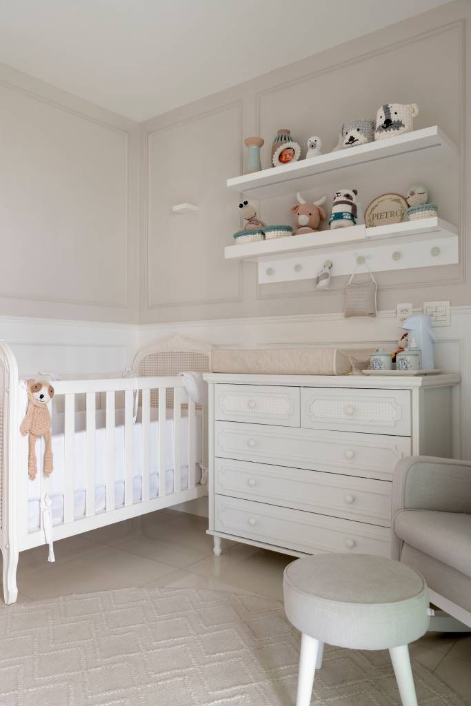 Quarto infantil; quarto de bebê branco com berço e prateleira de brinquedos.