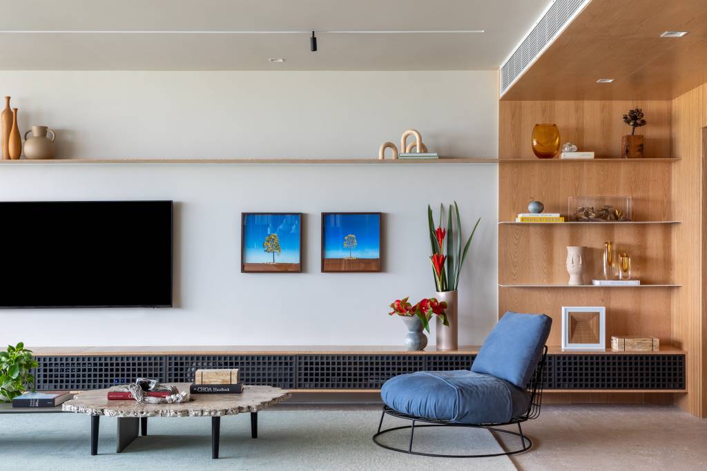 reforma-cria-coworking-sala-intima-ape-320m-up3-arquitetura-05-sala-poltrona-rack Sala de estar com poltrona azul, tapete claro, rack e prateleira.